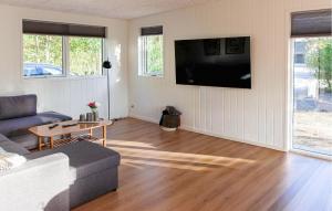 a living room with a couch and a flat screen tv at Amazing Home In Glesborg With Sauna in Fjellerup Strand