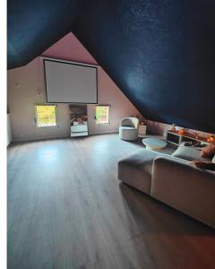 un salon avec un canapé et une télévision à écran plat dans l'établissement LOVEROOM - Le pavillon des arômes, à Aiserey