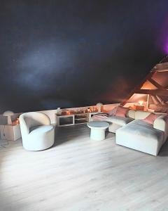 Elle comprend un salon doté d'un mobilier blanc et d'un mur noir. dans l'établissement LOVEROOM - Le pavillon des arômes, à Aiserey 4 autres photos