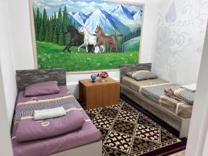 a room with two beds and a painting of horses at Милый дом in Tokmok