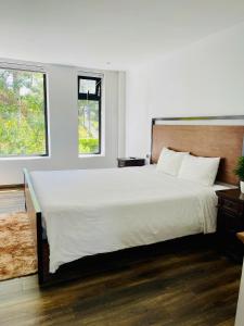 a bedroom with a large white bed with two windows at lalahouse6 in Khu Chi Lăng