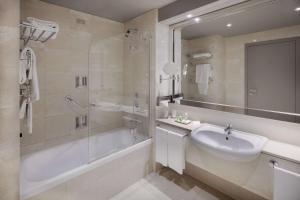 une salle de bain avec une baignoire, un lavabo et une douche dans l'établissement NH Torino Lingotto Congress, à Turin