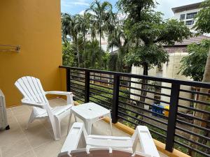 a balcony with two white chairs and a table at Kata Kata Stay in Kata Beach