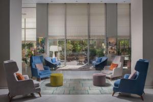 a lobby with chairs and tables and a large window at NH Torino Lingotto Congress in Turin