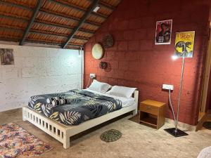 a bedroom with a bed in a red wall at Nomad's Nook in Ponnampet