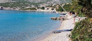 a beach with a group of people swimming in the water at Olcsica Apartment in Klenovica
