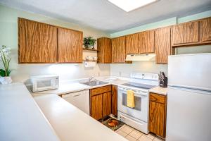 une cuisine avec des appareils électroménagers blancs et des armoires en bois dans l'établissement Pono Kai Resort J101, à Kapaa 31 autres photos