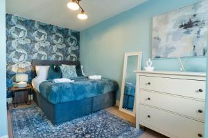 Un dormitorio azul con una cama y una cómoda. en The Tudor Escape Stylish City Centre 3 Bed, en Canterbury