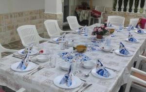 een tafel met witte stoelen en een blauw en wit tafelkleed bij Mile Ferienhaus in Rab