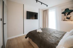 a bedroom with a bed with two white shoes on it at DG Apartamenty Bulwary-Apartament Sombrero Verde in Mielec