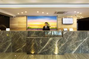 a man in a suit standing in front of a screen in a lobby at Lavande Hotel Suzhou Guanqian in Suzhou