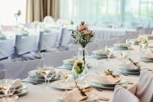 a table set up for a wedding with a vase of flowers at Wellness Hotel ABÁCIE in Nový Jičín