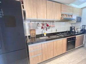 une cuisine avec des armoires en bois et un réfrigérateur en acier inoxydable dans l'établissement Apartamento simone 2 COP 30, à Água Boa