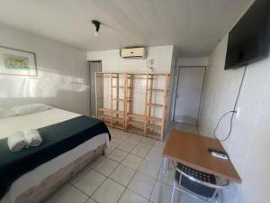 um quarto com uma cama, uma mesa e uma televisão em Pousada Casa Mar de Pajuçara em Maceió