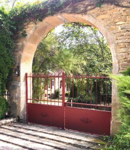an archway with a red gate in a garden at Les Eaux Calmes in Talcy