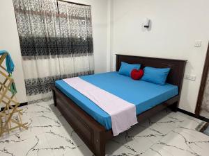 a bedroom with a bed with blue pillows and a window at Freedom Villa in Hikkaduwa