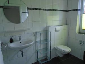 a bathroom with a sink and a toilet and a mirror at Ferienwohnung Hilbers in Horumersiel +3 photos