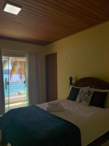 a bedroom with a bed with a view of the ocean at Carneiro's House in Praia de Araçatiba