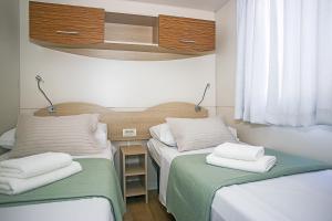 two beds in a small room with white towels on them at Auto-kamp Dvije suze 2 in Brištane +9 photos
