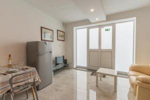 ein Wohnzimmer mit einem Kühlschrank und einem Tisch in der Unterkunft Cozy Apartment in Malta in St Paul's Bay