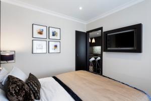 Schlafzimmer mit einem Bett und einem Flachbild-TV in der Unterkunft The Westbourne Hyde Park in London