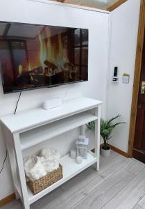 a living room with a fireplace and a tv at The Garden Gate Cabin in Wallington