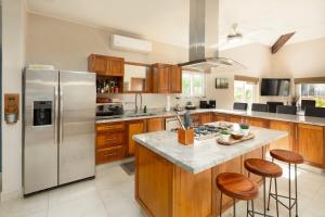 a kitchen with a stainless steel refrigerator and wooden cabinets at Gorgeous Penthouse across from Beach with Ocean Views! in Punta Mita