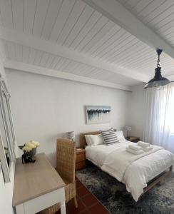 a white bedroom with a bed and a table at Wild Riverside Cottage in Velddrif