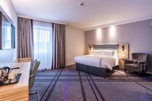 a hotel room with a bed and a chair at Premier Inn Hannover City University in Hannover