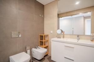 une salle de bain avec toilettes, lavabo et miroir dans l'établissement HolidaysPT - Sunset At Lux Terrace - 2 Bedroom Apt, à Faro