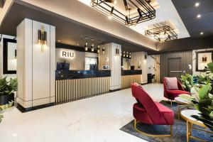a lobby with red chairs and a ru counter at Riu Plaza Toronto in Toronto