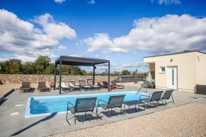 a swimming pool with chairs and a gazebo at Auto-kamp Dvije suze 2 in Brištane