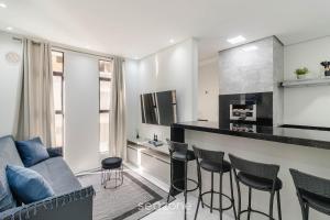 a living room with a couch and a bar with stools at Estadia completa a 500m do mar em Itapema - STWs in Meia Praia