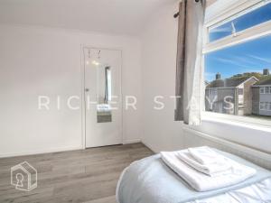 ein weißes Schlafzimmer mit einem Fenster und einem Bett in der Unterkunft Bright 2BR Terrace in Basildon, Garden and Amenities in Basildon