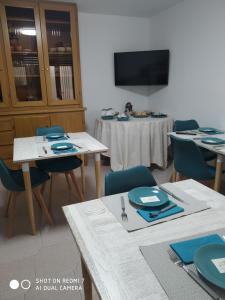 a dining room with tables and chairs and a tv at B&B MASSERIA U Saliére in Sarconi
