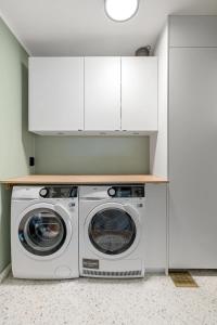 une laveuse et une sécheuse dans une cuisine avec des armoires blanches dans l'établissement The Royal Penthouse by Paramount, à Tromsø