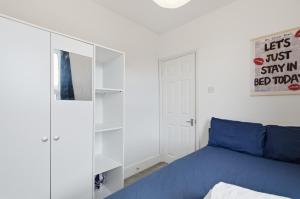 a bedroom with a blue bed and a mirror at Comfy 3 bed Home in London in Elmers End