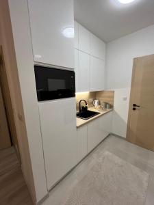 Una cocina blanca con fregadero y microondas. en Stan na dan TowerLife Gradačac, en Gradačac
