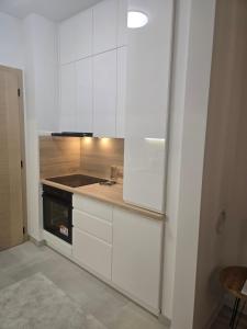 Una cocina con gabinetes blancos y una estufa. en Stan na dan TowerLife Gradačac, en Gradačac