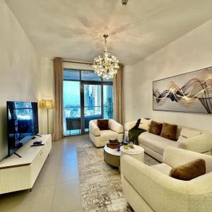 Una sala de estar con muebles blancos y una lámpara de araña. en Bellevue Towers Luxurious Burj Khalifa, Full Downtown & Old-town Views, en Dubái