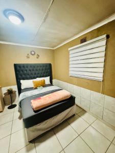 Un dormitorio con una cama y una ventana. en Tseleng Guest House, en Vosloorus
