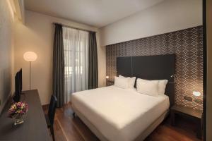 une chambre d'hôtel avec un grand lit et un bureau dans l'établissement NH Collection Torino Santo Stefano, à Turin