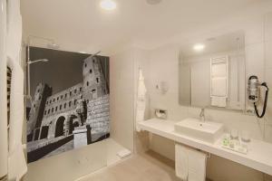 a white bathroom with a sink and a mirror at NH Collection Torino Santo Stefano in Turin