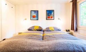 a bedroom with a bed with two pillows and two paintings at Recreatiepark het Esmeer in Aalst +29 photos