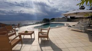 een zwembad met stoelen en een tafel en een parasol bij Luxury Villa with Pool and Garden in Ricadi