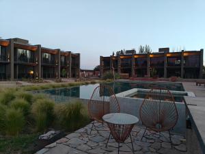 two chairs and a table in front of a building at Vistalba Hotel Aparts & Suites in Ciudad Lujan de Cuyo
