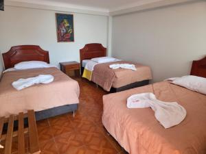 een kamer met drie bedden en handdoeken erop bij Inkas Hotel Cusco in Cuzco +11 foto's