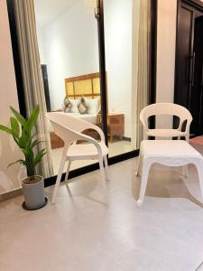 a room with two white chairs and a bed at Madushan Garden & Villa in Weligama