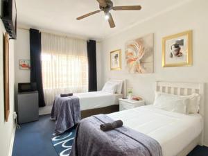 ein Schlafzimmer mit zwei Betten und einem Deckenventilator in der Unterkunft Terrys Cozy Homestay in Germiston