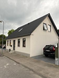 a white house with a car parked in front of it at Isabella 7 personers hus in Hjørring